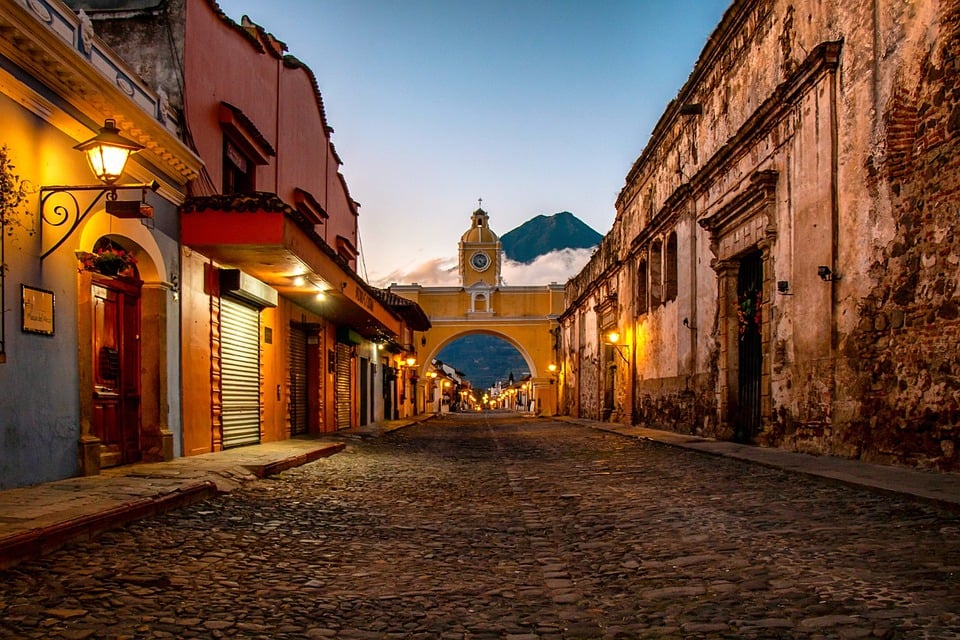 Arco de Santa Catalina en Antigua Guatemala, calle empedrada iluminada al atardecer